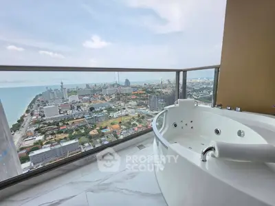 Luxurious balcony with jacuzzi offering stunning city and ocean views in high-rise apartment.