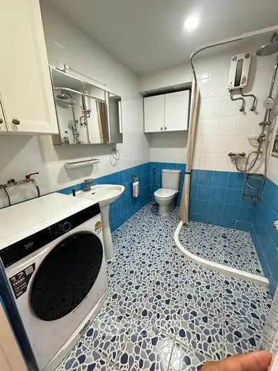 Modern bathroom with washing machine and shower in a stylish blue and white design.