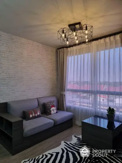 Chic urban living room with exposed white brick wall, modern grey sofa, and stylish zebra-pattern rug, complemented by a unique geometric ceiling light fixture.