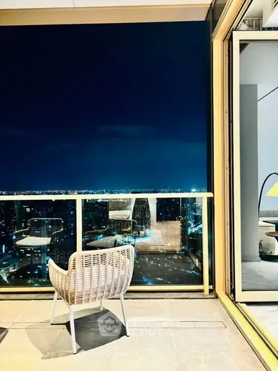 Luxurious high-rise balcony with stunning night city view and elegant outdoor seating.
