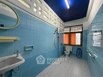Spacious blue-tiled bathroom with modern fixtures and natural light.