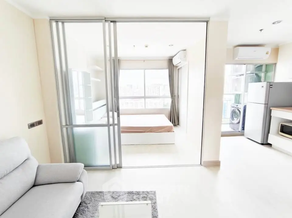 Modern open-plan apartment with sliding glass doors, bright living area, and city view.