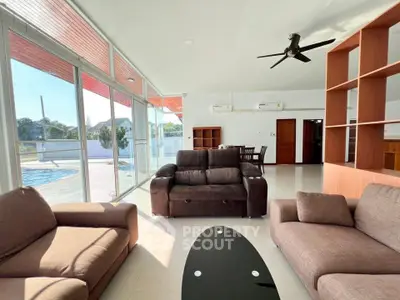 Spacious living room with modern furniture and pool view, perfect for relaxation and entertainment.