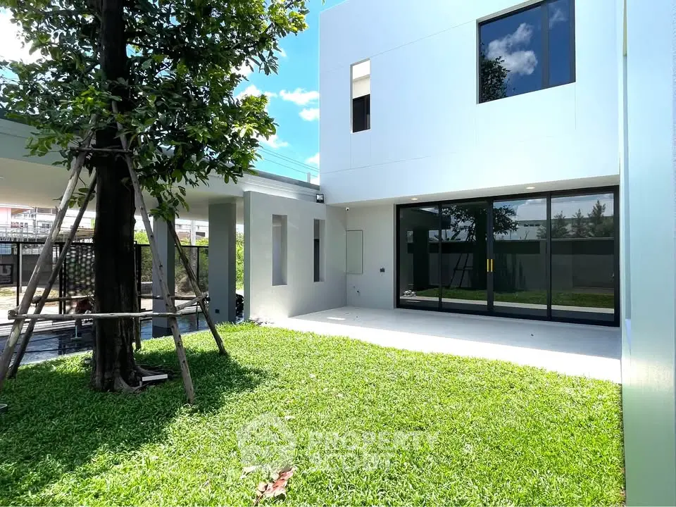 Modern home exterior with lush green lawn and large windows, perfect for family living.