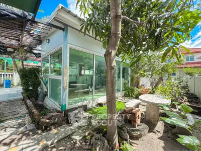Charming garden view with modern glass-walled structure, perfect for relaxation or creative workspace.