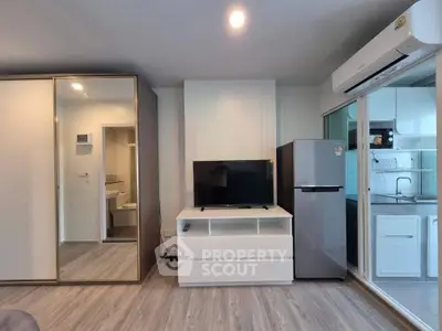 Modern apartment interior with sleek kitchen and stylish living area featuring a TV and air conditioning.
