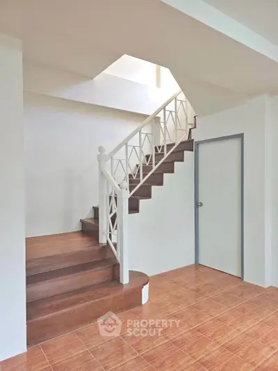 Elegant staircase with wooden steps and white railing in a modern home interior.