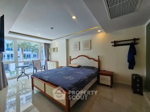 Spacious bedroom with large windows and modern furnishings in a stylish apartment.