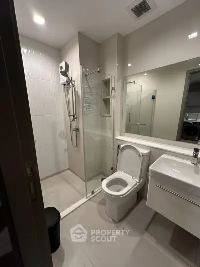 Modern bathroom with glass shower and sleek fixtures in contemporary apartment.