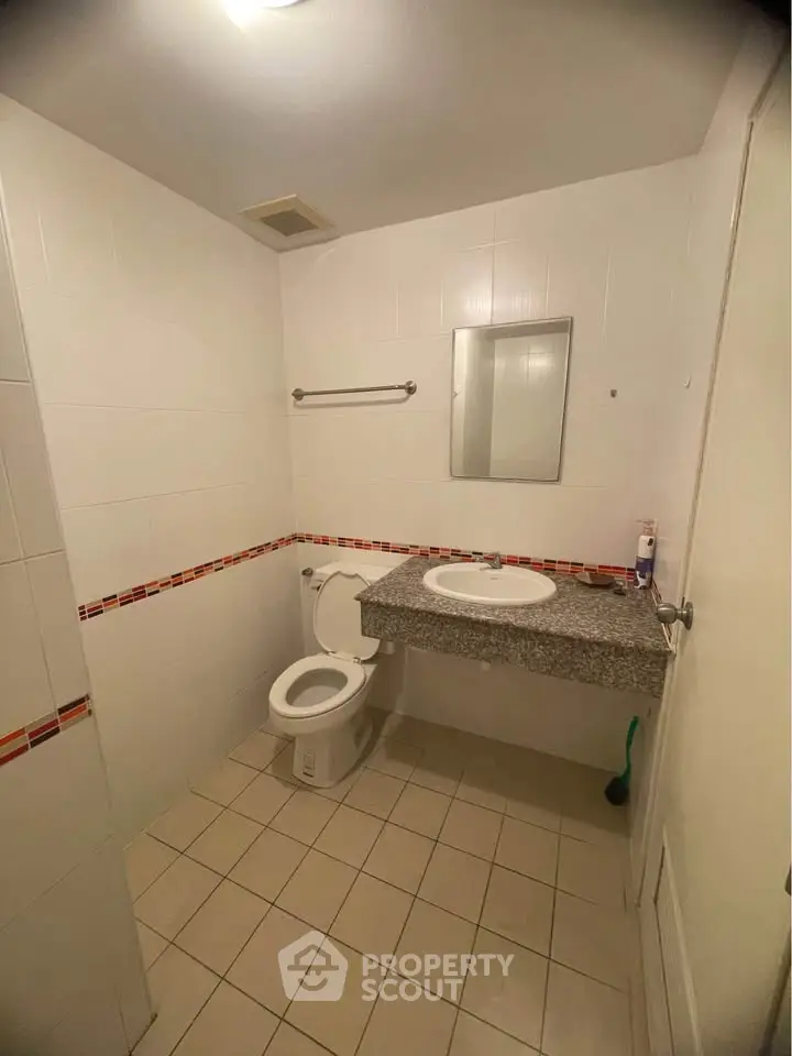 Spacious bathroom with modern fixtures and tiled walls in a real estate property.