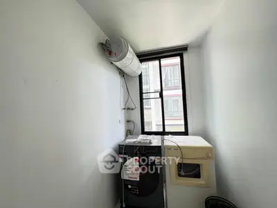Compact laundry room with washer, dryer, and water heater in a bright space.