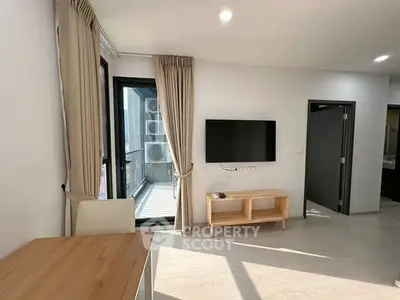 Modern living room with balcony access and wall-mounted TV in a bright apartment.