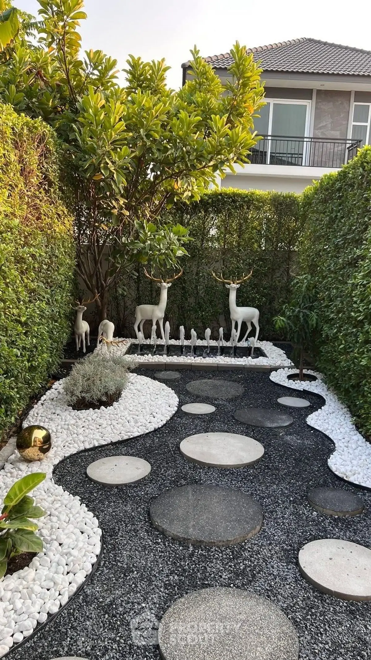 Charming garden with decorative deer statues and modern stone pathway in a serene residential setting.