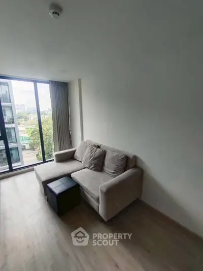 Modern living room with cozy sofa and large window offering city view.