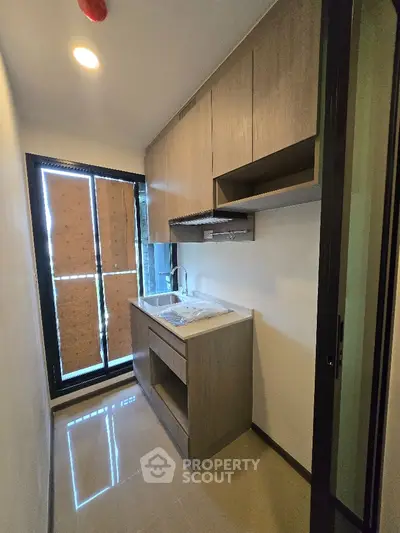 Modern compact kitchen with sleek cabinetry and large window for natural light