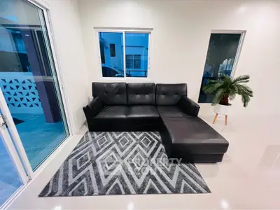 Modern living room with black leather sectional sofa and geometric rug