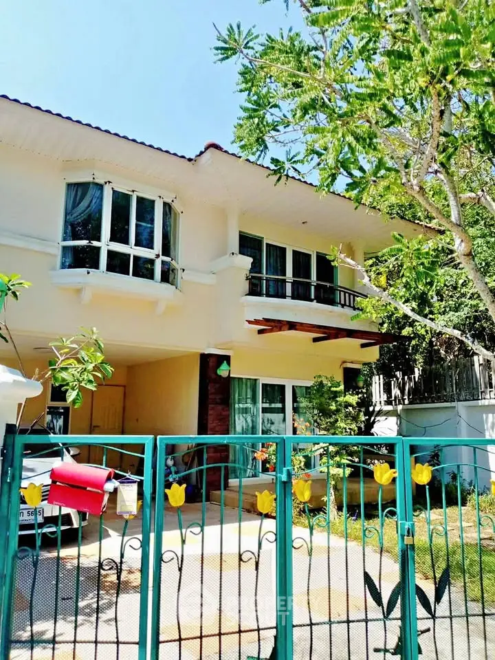 Charming two-story house with lush garden and gated entrance, perfect for family living.