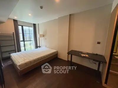 Spacious bedroom with large window and modern furnishings in a stylish apartment.