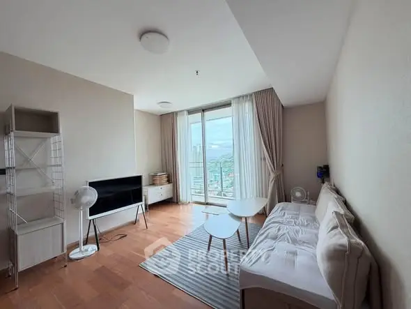 Spacious living room with modern decor and city view, featuring a cozy sofa and sleek TV setup.