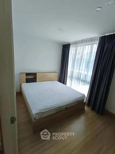 Spacious bedroom with large window and modern wooden flooring