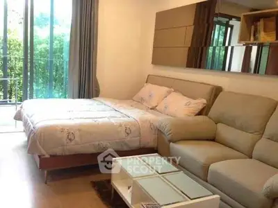 Cozy bedroom with balcony view, featuring a comfortable bed and stylish sofa in a modern apartment.