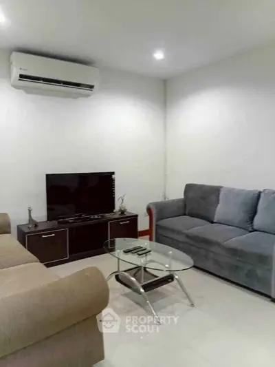 Cozy living room with modern furniture and air conditioning, perfect for relaxation.