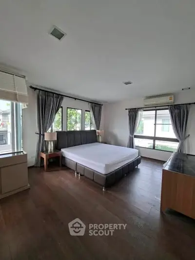 Spacious bedroom with large windows and modern furnishings, offering a bright and airy atmosphere.