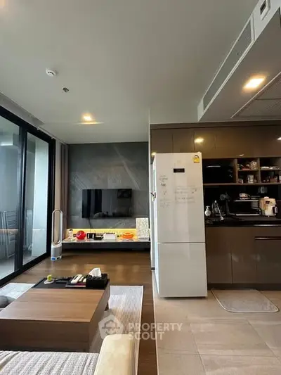 Modern living room with open kitchen, featuring sleek appliances and a cozy seating area.