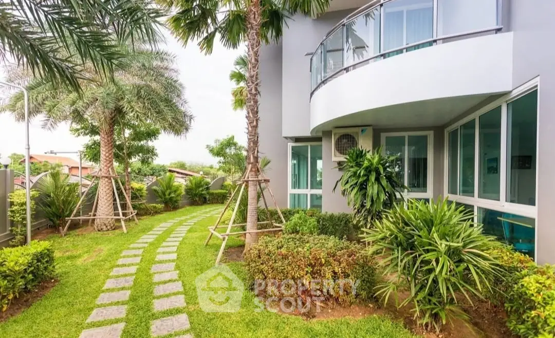 Modern building exterior with lush garden and curved balcony design.
