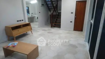 Modern interior with hexagonal tiles and wooden furniture, featuring a staircase and washing machine.