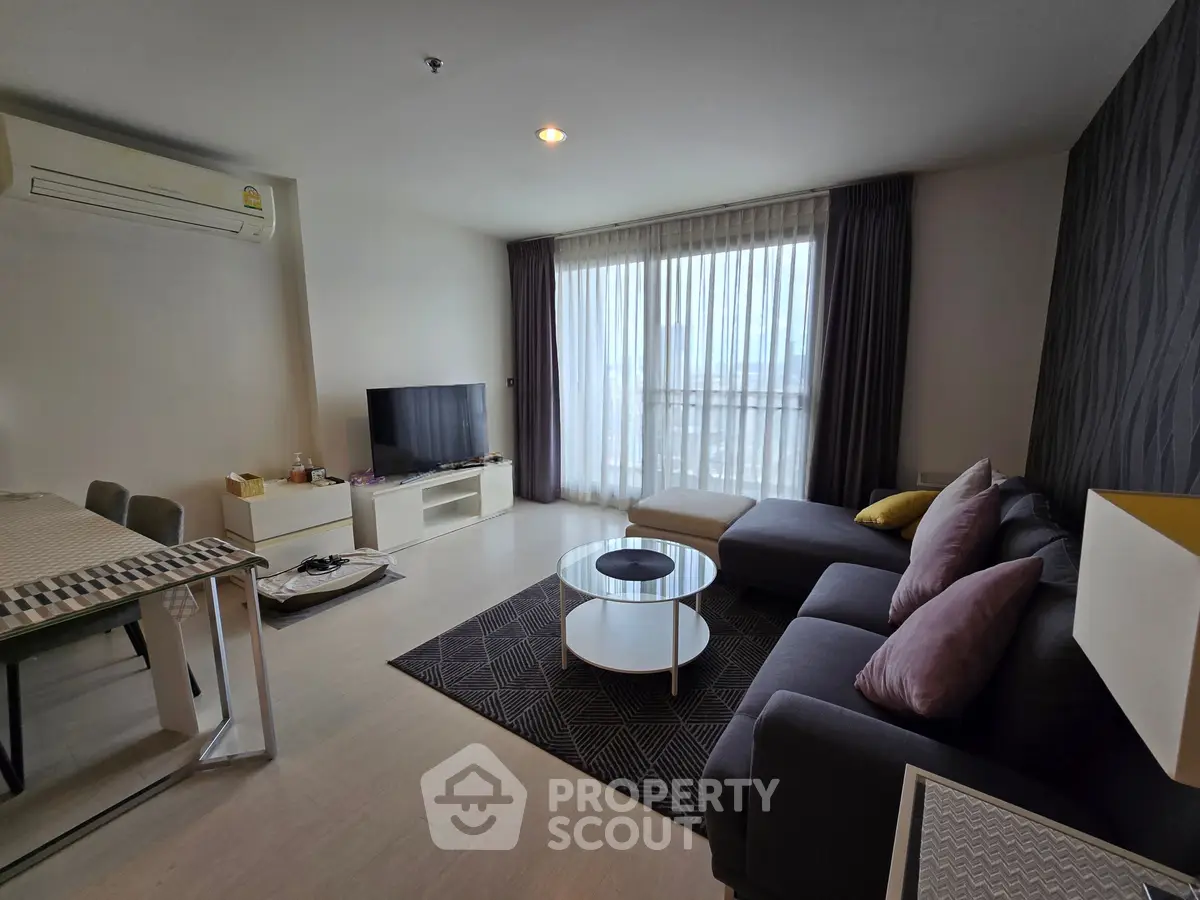 Spacious modern living room with large windows and stylish furniture in a high-rise apartment.