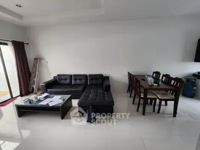 Spacious living room with modern black leather sofa and dining area