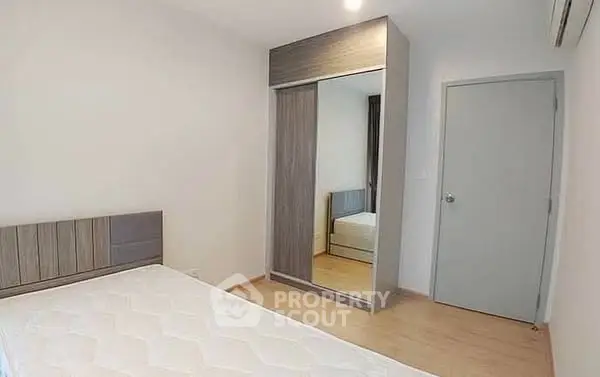 Minimalist bedroom with mirrored wardrobe and wooden flooring