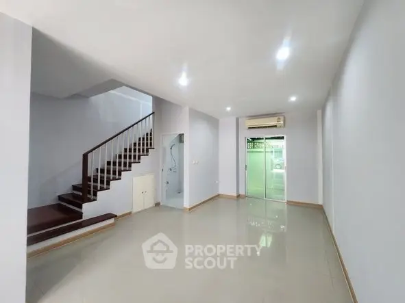 Spacious modern living room with staircase and air conditioning, perfect for family gatherings.