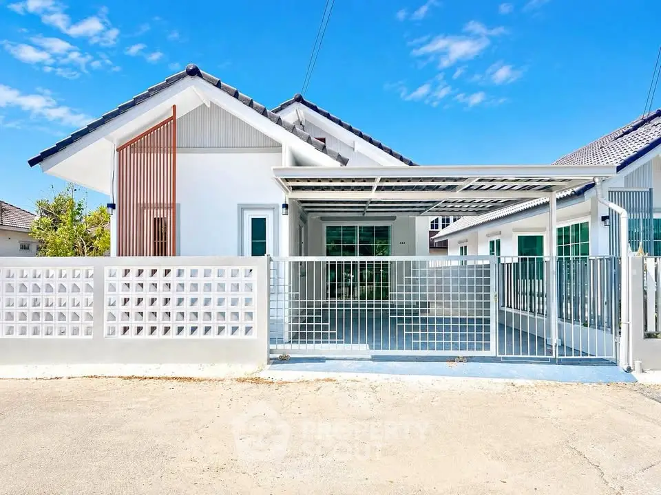 Charming single-story house with modern design and spacious carport under clear blue sky.