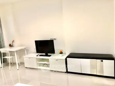 Modern minimalist living room with sleek white furniture and a flat-screen TV.