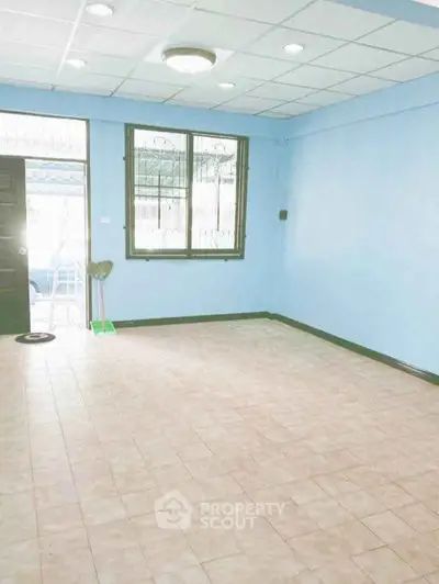 Spacious empty room with tiled floor and blue walls, ideal for customization.