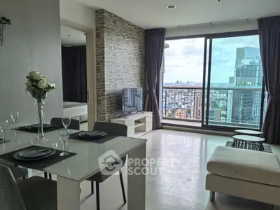 Modern living room with city view, elegant dining setup, and stylish decor in high-rise apartment.