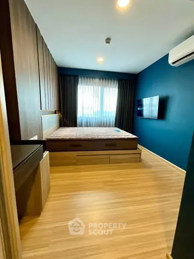 Modern bedroom with wooden flooring, stylish bed, and wall-mounted TV in a cozy apartment.