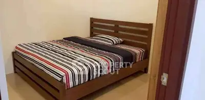 Cozy bedroom with wooden bed frame and striped bedding in a minimalist design.