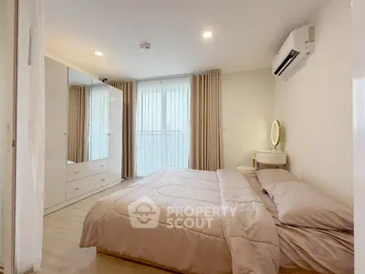 Modern bedroom with cozy bedding, mirrored wardrobe, and air conditioning.