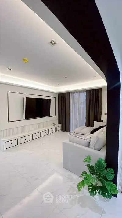 Modern living room with sleek design, large TV, and elegant lighting.
