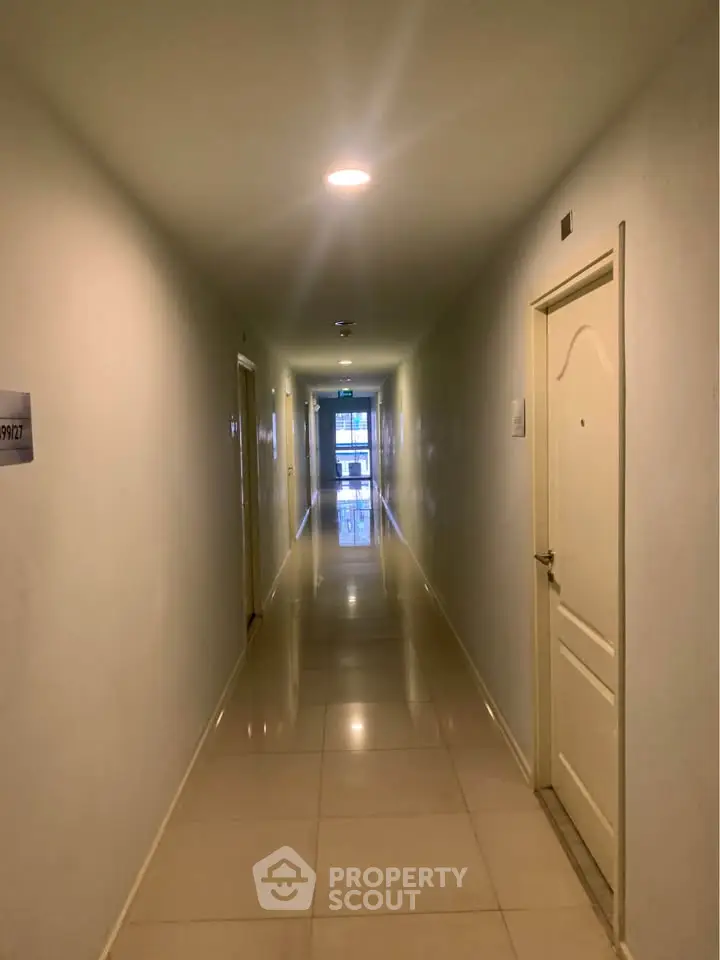 Spacious and well-lit apartment corridor with glossy tiled flooring.