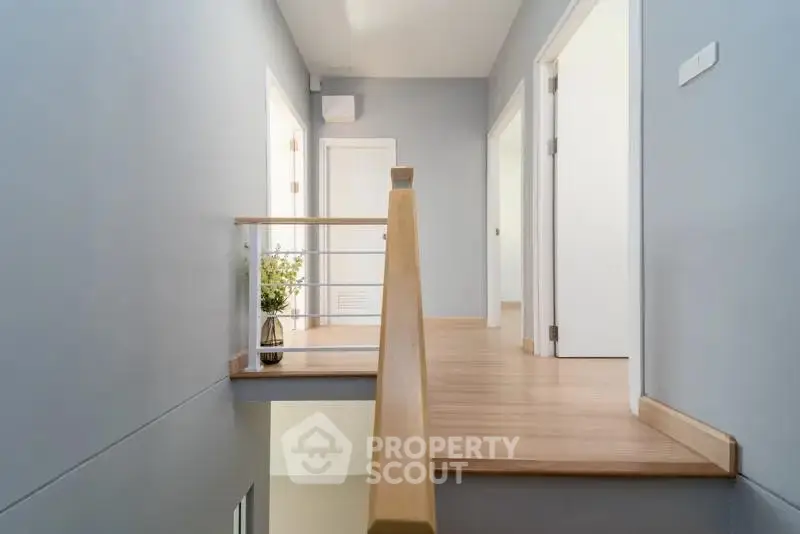 Modern hallway with wooden flooring and stylish railing in a contemporary home.