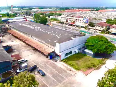 Aerial view of spacious warehouse with ample parking and surrounding greenery, ideal for logistics or storage.