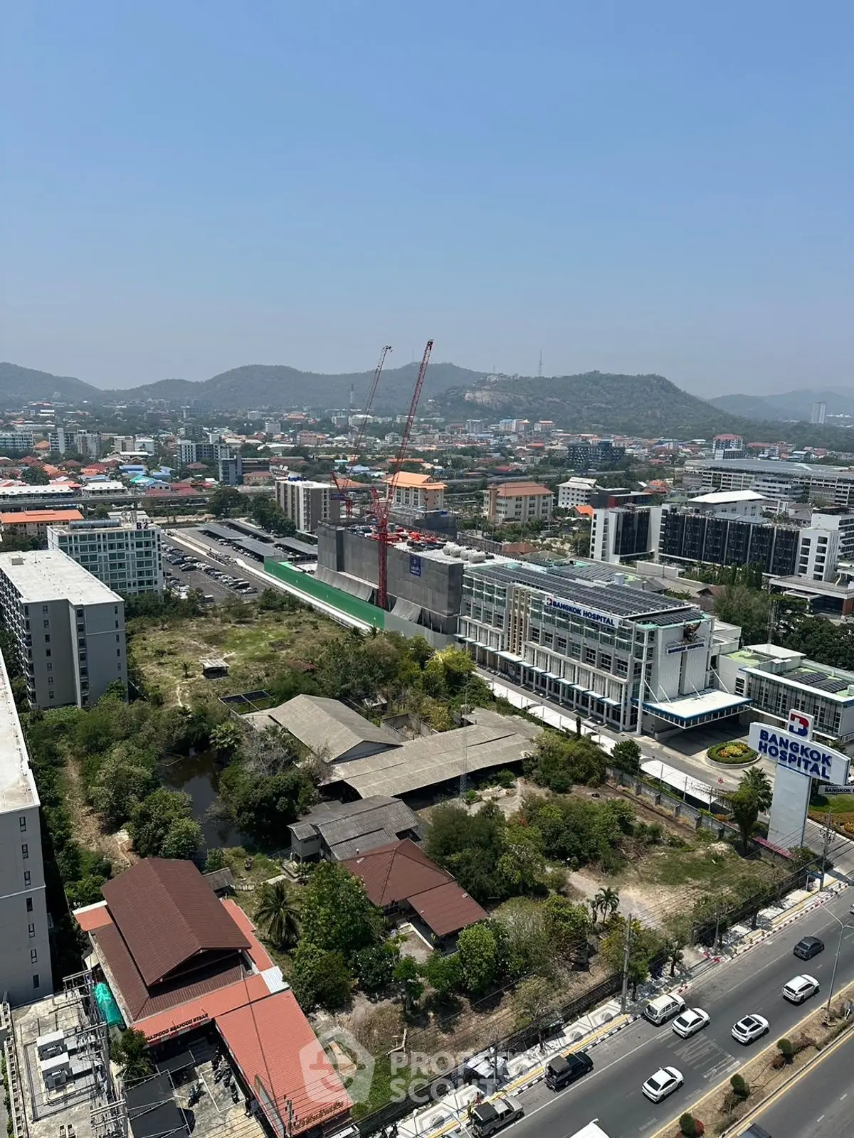 Panoramic city view with construction site and distant hills, showcasing urban development.