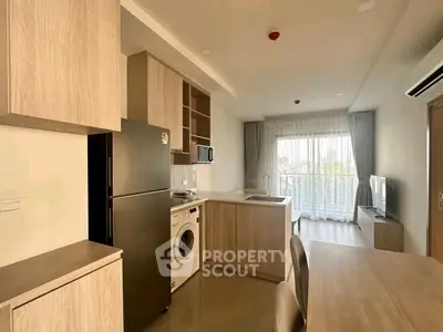 Modern open-layout kitchen with appliances and bright living area leading to balcony.