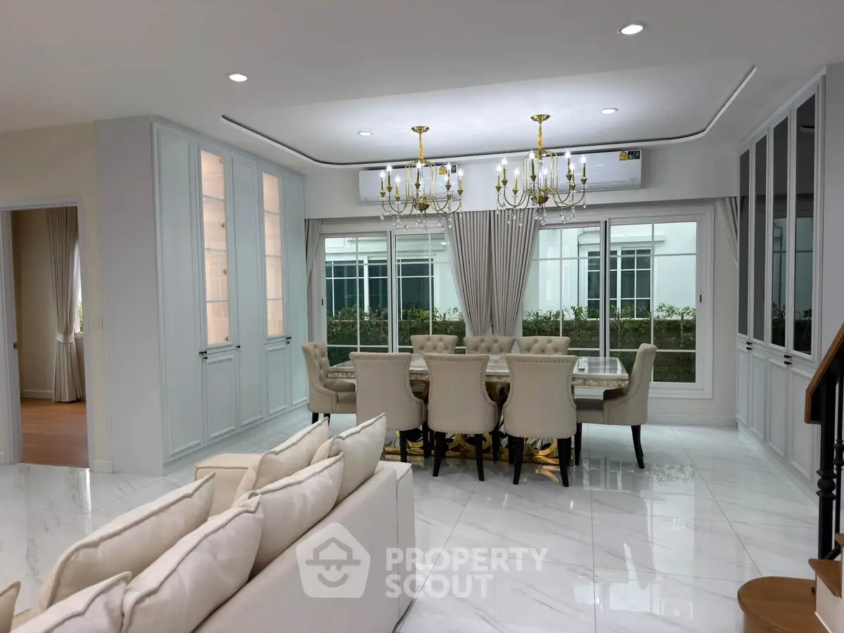 Luxurious open-plan living and dining area with elegant chandeliers and large windows.