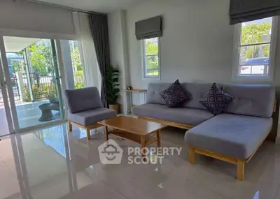Modern living room with sleek furniture and large windows offering natural light and garden view.