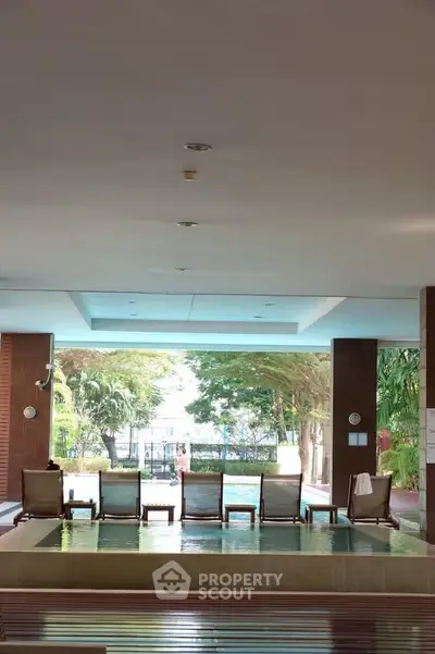 Luxurious indoor pool area with lounge chairs and lush greenery view.